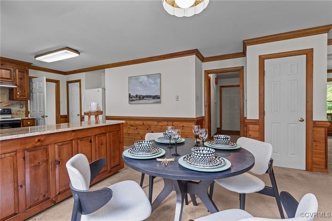 Dining room featuring a wainscoted wall, ornamental molding, wooden walls, and light carpet | Image 11