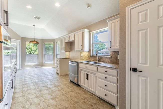 Kitchen with stainless steel dishwasher, a wealth of natural light, a sink, visible vents, and lofted ceiling | Image 17