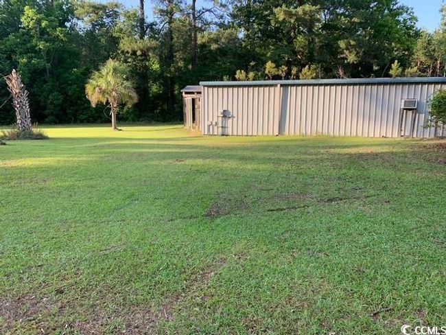 View of grassy yard featuring an outbuilding and view of wooded area | Image 28