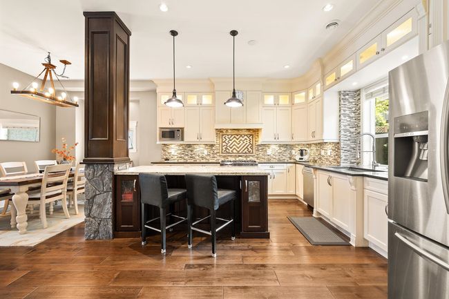 Kitchen featuring appliances with stainless steel finishes, backsplash, dark wood finished floors, light stone counters, and recessed lighting | Image 9