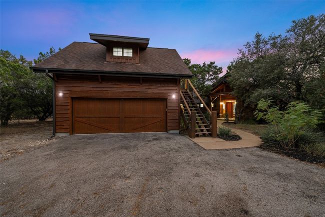 The two-story detached garage offers ample parking and storage, with a charming wood exterior that complements the home’s rustic style. An exterior staircase leads to a private upper-level entry, ideal for guest accommodations or additional living space. | Image 27