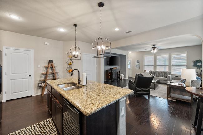 Kitchen with arched walkways, dark wood-style floors, a sink, and black dishwasher | Image 15