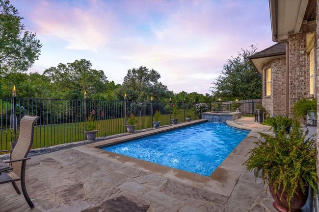 Pool at dusk featuring a patio, a fenced backyard, and a pool with connected hot tub | Image 30