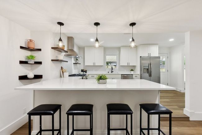 Kitchen with a breakfast bar, a peninsula, wall chimney exhaust hood, and stainless steel appliances | Image 7