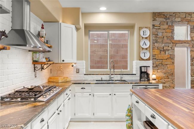 Kitchen with open shelves, wall chimney exhaust hood, a sink, wooden counters, and appliances with stainless steel finishes | Image 14