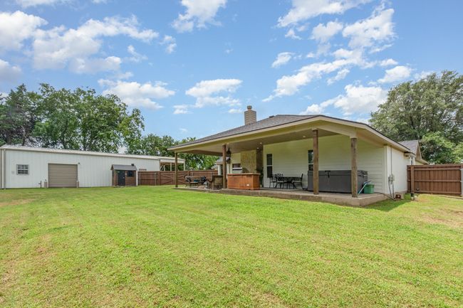 Rear view of property featuring a hot tub, a chimney, a patio, and a detached garage | Image 34