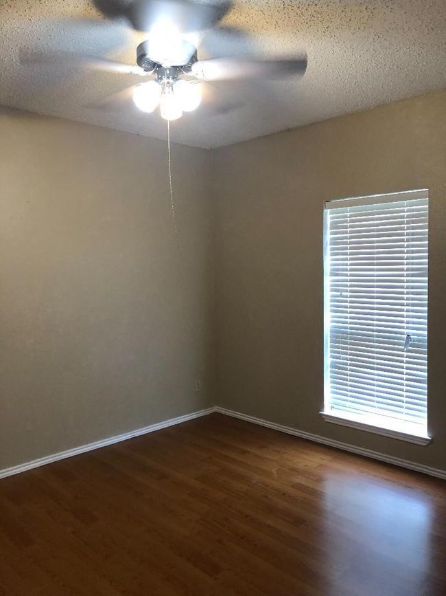 Spare room featuring dark wood-style floors, a ceiling fan, baseboards, and a textured ceiling | Image 6