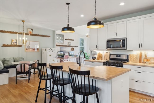 Kitchen featuring white cabinets, a notable chandelier, butcher block countertops, and stainless steel appliances | Image 12