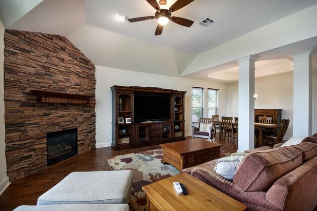 Living room featuring decorative columns, ceiling fan, a fireplace, wood finished floors, and baseboards | Image 7