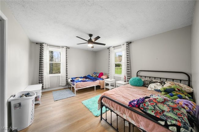Bedroom featuring a textured ceiling, multiple windows, ceiling fan, and wood finished floors | Image 14