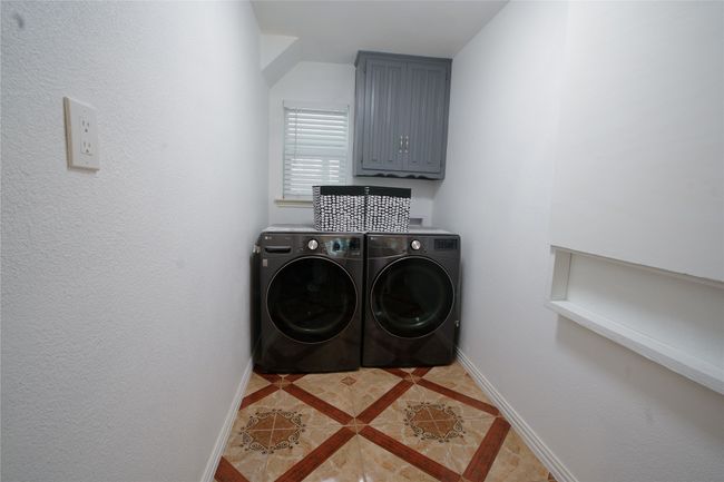 Washroom featuring independent washer and dryer, inlaid floor details, light tile patterned floors, and cabinet space | Image 27