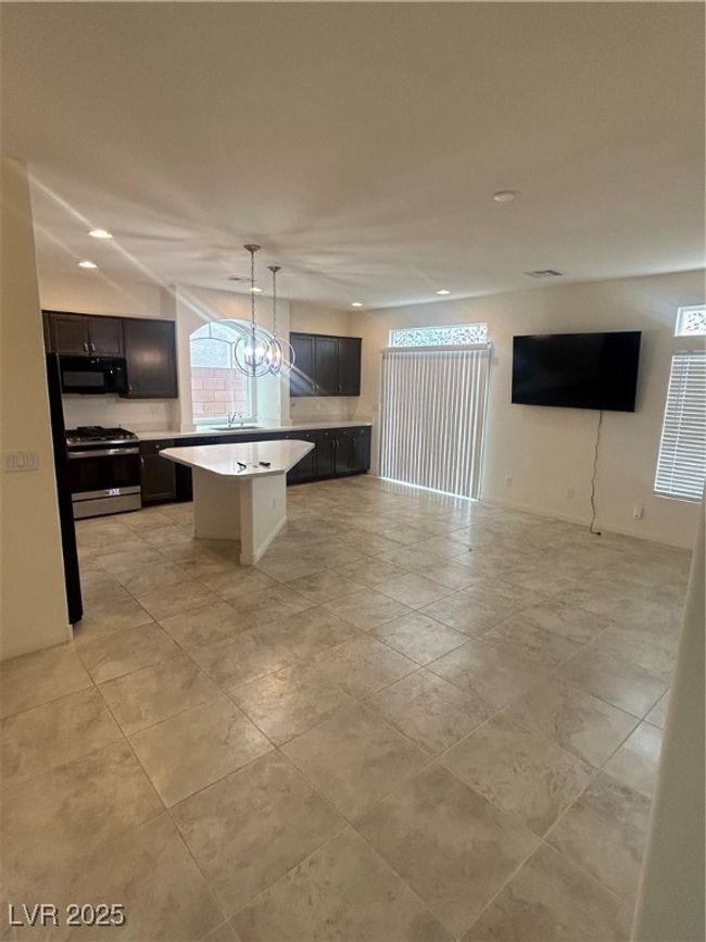Kitchen featuring range, open floor plan, a center island, light countertops, and a sink | Image 9
