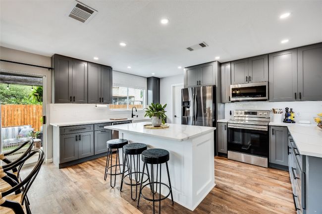 Kitchen with appliances with stainless steel finishes, gray cabinetry, a breakfast bar area, tasteful backsplash, and recessed lighting | Image 15