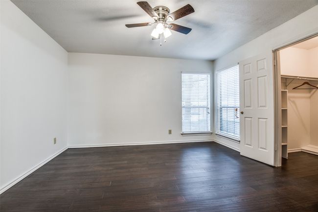 Unfurnished bedroom with a walk in closet, dark wood finished floors, and baseboards | Image 12