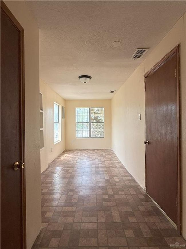 Spare room with a textured ceiling, visible vents, and brick patterned floor | Image 14