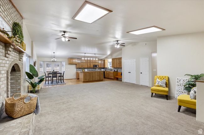 Living room with lofted ceiling, a brick fireplace, light colored carpet, and ceiling fan | Image 6