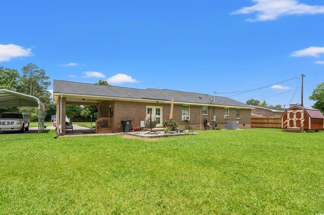 Back of house with a storage unit, brick siding, a detached carport, a patio, and french doors | Image 21