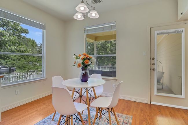 Dining space featuring healthy amount of natural light, wood finished floors, and a chandelier | Image 11