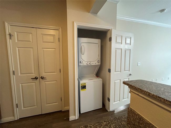 Laundry area featuring dark wood-style floors, laundry area, stacked washer and dryer, and crown molding | Image 8