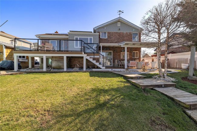 Back of property with fence, stairs, brick siding, a yard, and a patio area | Image 33