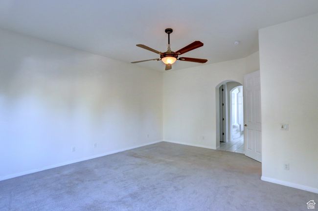 Carpeted empty room featuring arched walkways, baseboards, and a ceiling fan | Image 10