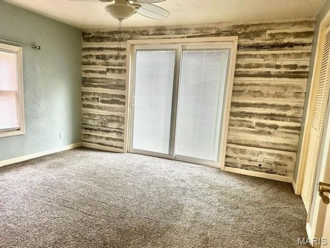Unfurnished bedroom featuring carpet flooring, a closet, ceiling fan, and wood walls | Image 27