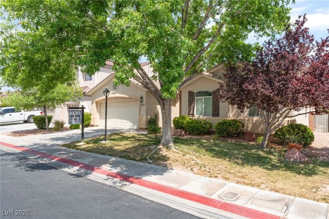 View of property hidden behind natural elements with driveway, stucco siding, a garage, and a front yard | Image 4