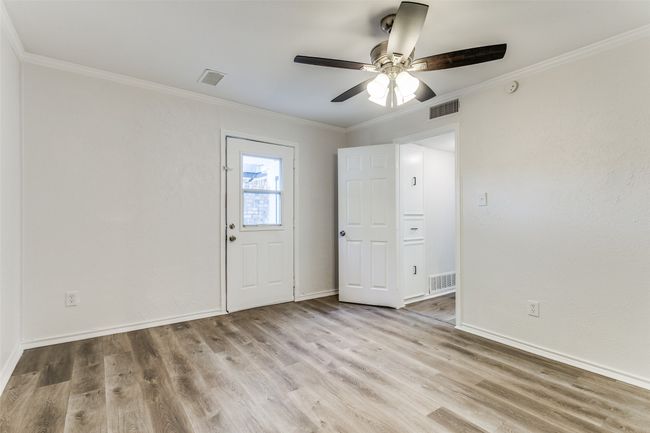 Empty room with wood finished floors, visible vents, ceiling fan, and crown molding | Image 18