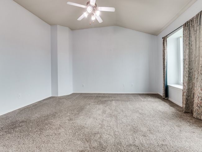 Carpeted empty room with lofted ceiling, ceiling fan, and baseboards | Image 17