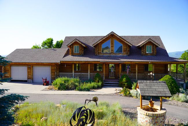 Log home featuring a porch, a garage, concrete driveway, log exterior, and roof with shingles | Image 4
