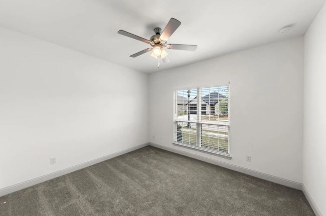Carpeted empty room featuring a ceiling fan and a smoke detector | Image 12