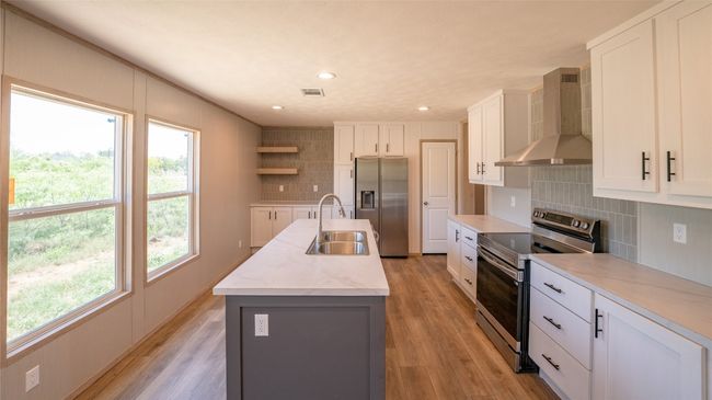 Kitchen with appliances with stainless steel finishes, wall chimney range hood, open shelves, light wood-style floors, and recessed lighting | Image 24