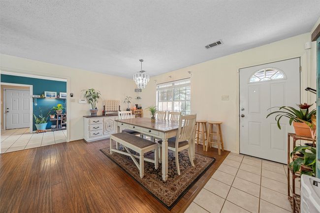 Dining area featuring light tile patterned flooring, a textured ceiling, visible vents, and an inviting chandelier | Image 11