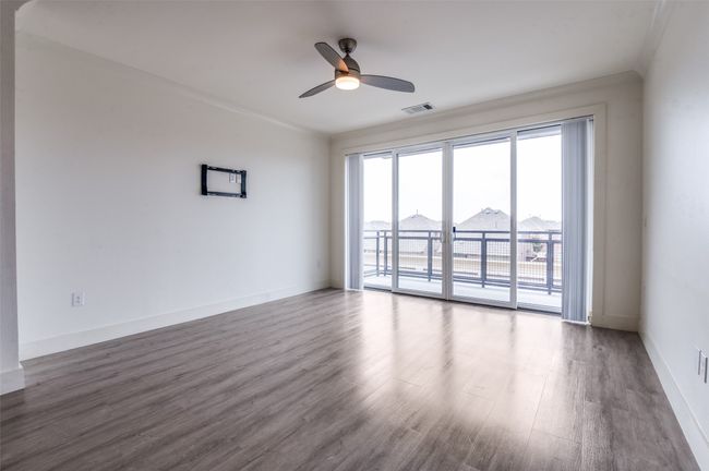 Empty room with a ceiling fan, wood finished floors, and ornamental molding | Image 14