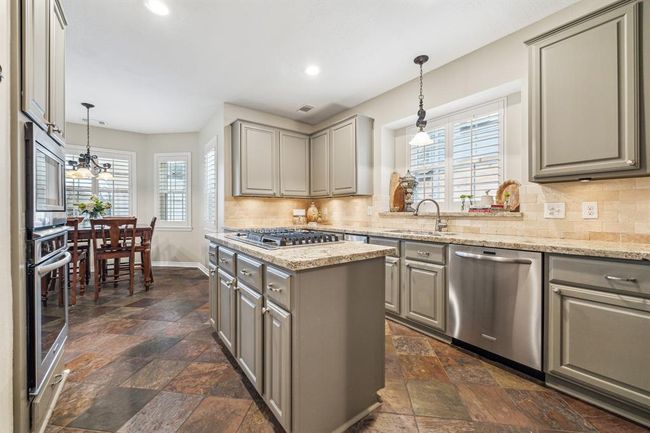 Experience culinary delight in this stylish kitchen with elegant slate floors and ample workspace. | Image 15