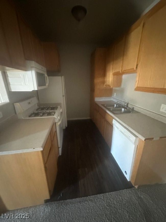 Kitchen with stove, dishwashing machine, a sink, dark wood-type flooring, and light countertops | Image 4