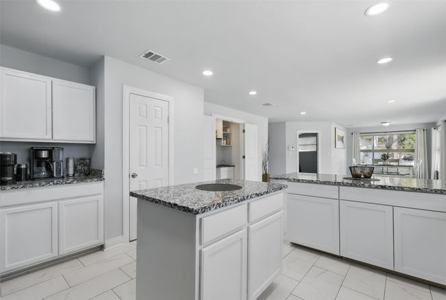 Kitchen with recessed lighting, dark stone counters, white cabinetry, and a center island | Image 5
