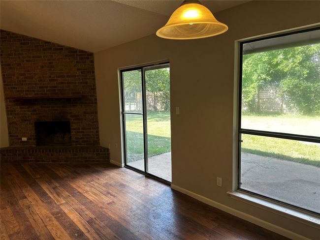 Unfurnished living room with lofted ceiling, a brick fireplace, and hardwood / wood-style flooring | Image 8