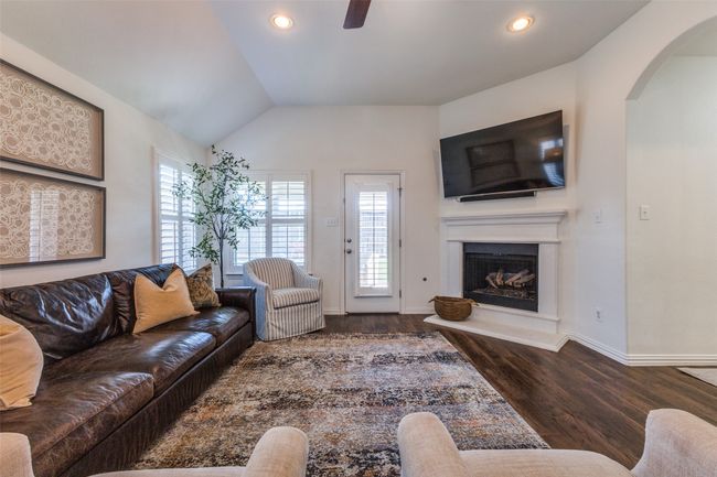 Large family room with corner fireplace. Plantation shutters throughout the home. | Image 8