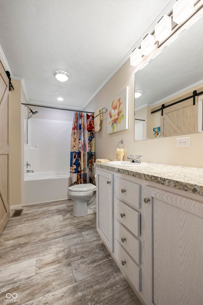 full bath featuring toilet, vanity, shower / tub combo, ornamental molding, and wood finished floors | Image 25