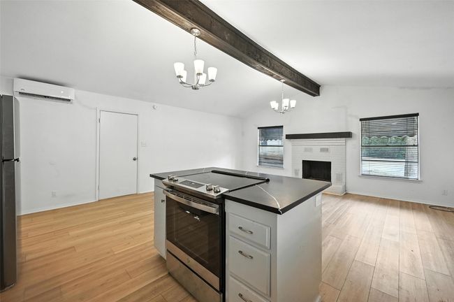 Kitchen with electric stove, an AC wall unit, a chandelier, dark countertops, and freestanding refrigerator | Image 13