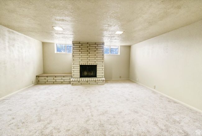Below grade area with a fireplace, a textured ceiling, and carpet floors | Image 22