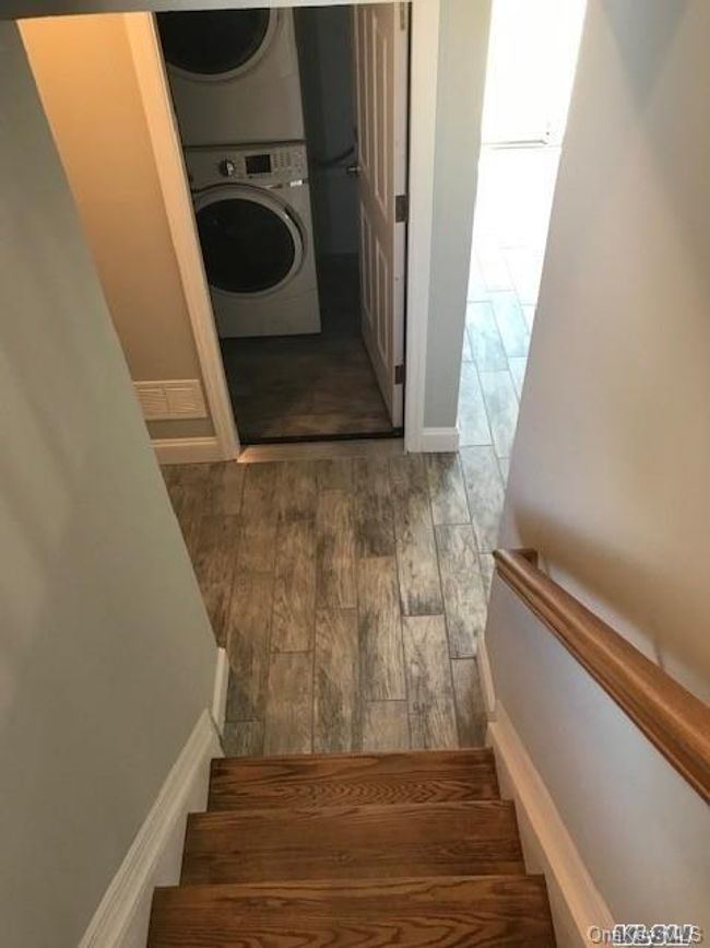 Stairs with wood finished floors and stacked washer / drying machine | Image 13