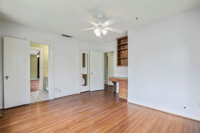 Unfurnished bedroom with light wood-style flooring, baseboards, connected bathroom, and ceiling fan | Image 11