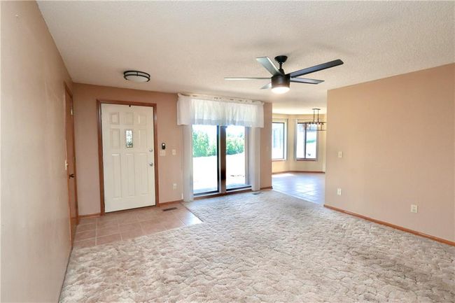 Entrance foyer featuring ceiling fan, a chandelier, light tile patterned floors, a textured ceiling, and light carpet | Image 29