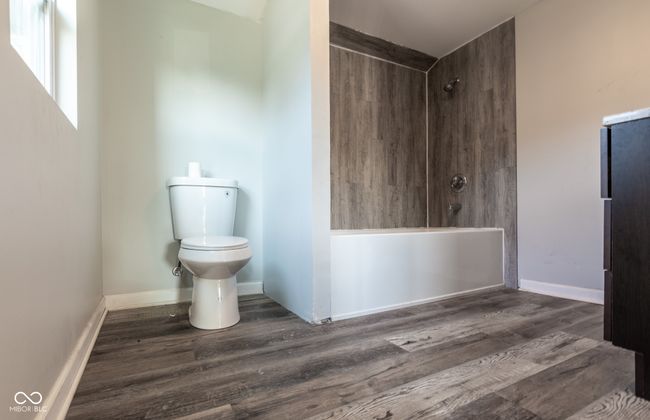 bathroom with toilet, baseboards, walk in shower, and wood finished floors | Image 36