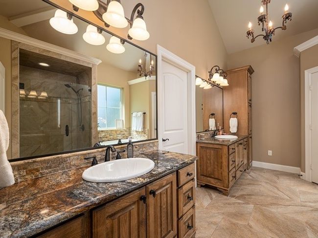 Full bath featuring two vanities, a shower stall, lofted ceiling, and a sink | Image 19