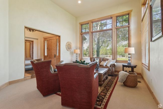 Carpeted living area featuring baseboards, a towering ceiling, and recessed lighting | Image 7