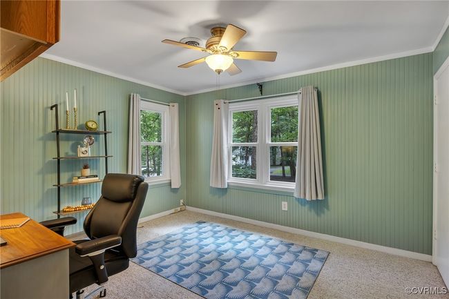 Carpeted bedroom/home office with crown molding, wood paneling, and ceiling fan with light | Image 23
