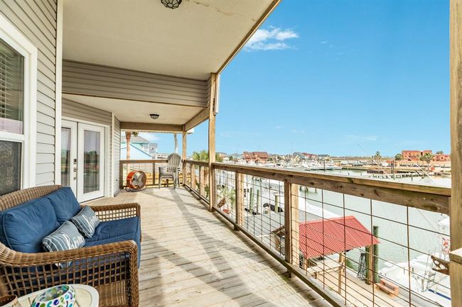 This photo showcases a spacious wooden deck with comfortable seating, overlooking a marina. The view includes boats docked along the water and nearby buildings. It's an inviting space for relaxation and enjoying waterfront living. | Image 33